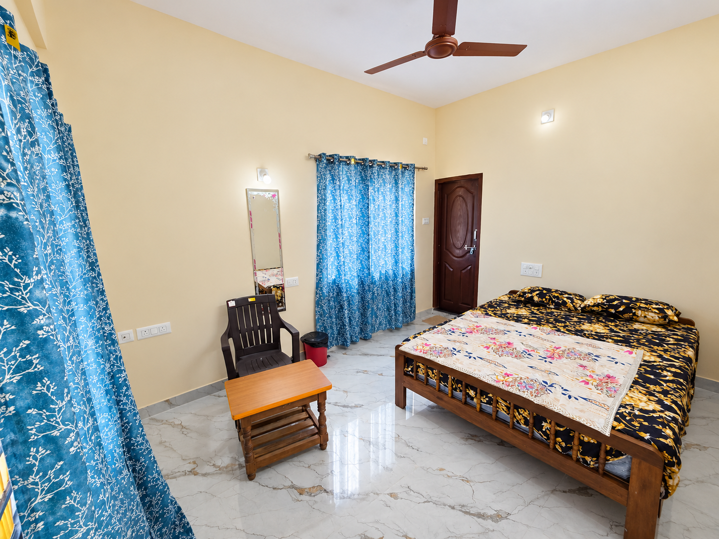 Single room with a wooden bed, a seating corner and a wall mirror