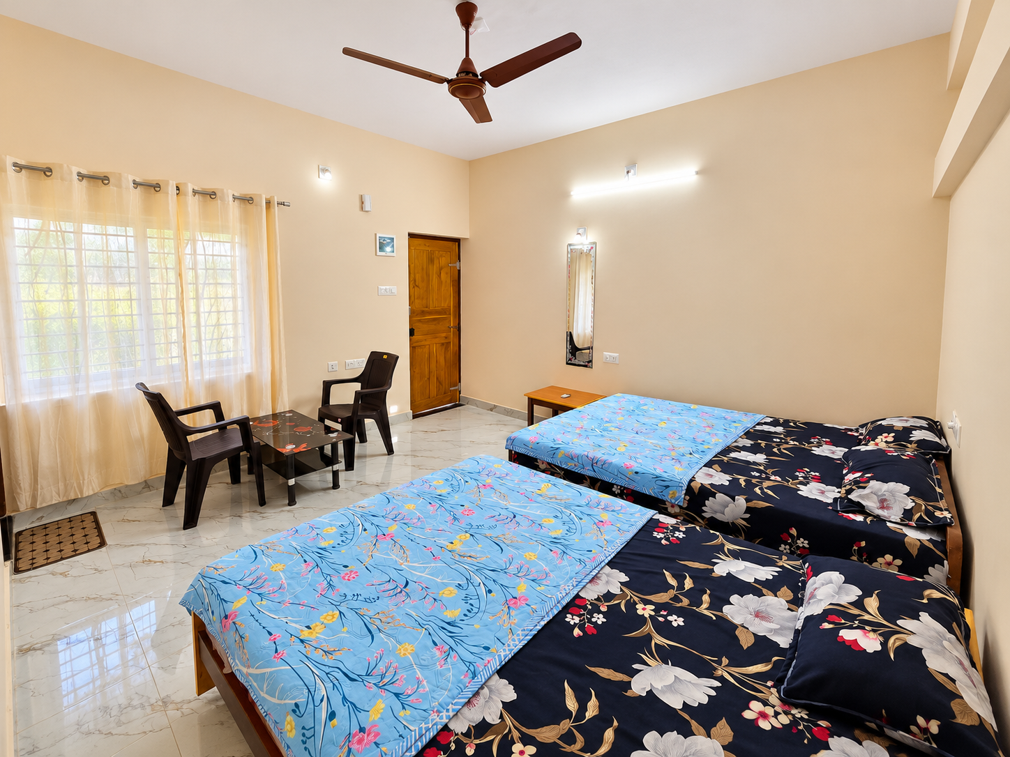Double room with two beds, a seating corner and a wall mirror