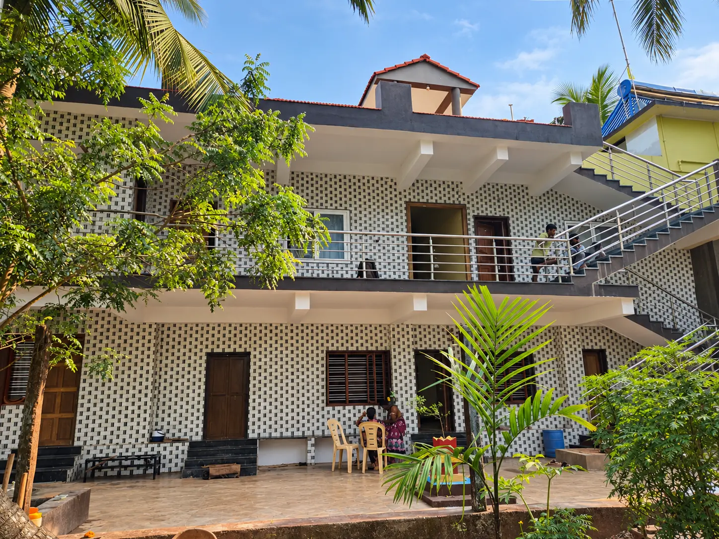 Front of the homestay with a paved patio where guests are seated